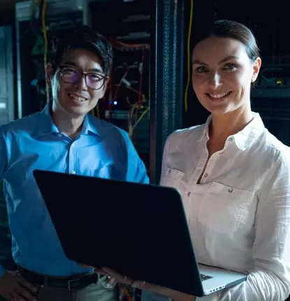 Infinity Tech Consulting professionals reviewing laptop data in server room with network equipment and cabling infrastructure visible