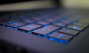 Infinity Tech Consulting backlit laptop keyboard with blue illumination showing function keys on modern computer workstation
