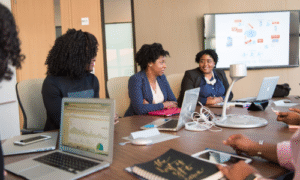 Infinity Tech Consulting team of professionals collaborating during business meeting with laptops in modern conference room in GA.